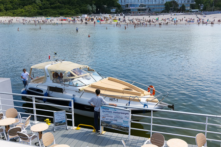 Kolobrzeg, Poland - June 11, 2017: The motor yacht arriving to the pier after cruise held on waters of the Baltic Sea. There are many people in a distance on a beachのeditorial素材