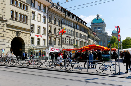 Bern, Switzerland - April 20, 2017: Bicycles are parked next the railing separating the square from the street. On the square there are many stalls and in the background you can see many tenements.のeditorial素材