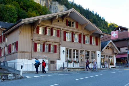 Lauterbrunnen, Switzerland - 21 September 2017: Old wooden home, which dates back to the mid-seventeenth century, is seen next to the street and at the back there is a rocky wall of the mountain.のeditorial素材