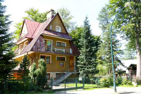 Zakopane, Poland - August 18, 2017: A building with a steep, sloping roof is covered with sheet metal. This house now called Ustronie is seen among trees and behind the fence.のeditorial素材