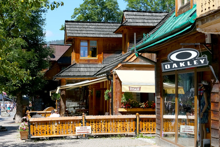 Zakopane, Poland - August 08, 2017: Wooden traditional buildings at Krupowki Street. Behind the wooden fence there is an outdoor part of the local restaurantのeditorial素材
