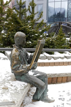 Zakopane, Poland - March 19, 2018: A highlander sitting on a rock and reading a newspaper, this is a bronze figure, created on the occasion of the 20th anniversary of the existence of a local magazineのeditorial素材