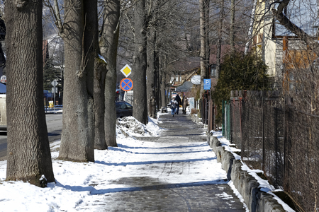 Zakopane, Poland - March 22, 2018: Street view during the winter season. It is one of the streets with old trees and people in the distance who can be seen.のeditorial素材