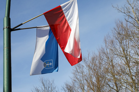 Zakopane, Poland - November 09, 2018: Two flags placed on a mast are waving in the wind. There are white and red flag of Poland together with the blue and white flag with the coat of arms of Zakopaneのeditorial素材