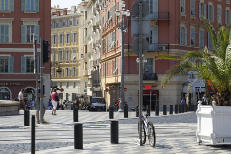 Nice, France - September 21, 2018: Massive tenement houses in the immediate vicinity of Massena Square. There are walking people, somebody left a bike by metal post, the life of the city is going on.のeditorial素材