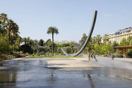 Nice, France - September 18, 2018: Arc de Venet, a metal sculpture by Bernar Venet (1988) was placed in the Gardens of Albert I right next to the famous Massen Square. Nearby there are walking people.のeditorial素材