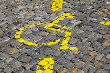 The wheelchair, which is a symbol of a disabled parking space, has been painted in yellow on a cobbled road surface .の写真素材