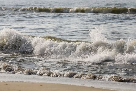 Splashing waves of the sea can be observed during strong winds. Here in Kolobrzeg such a wave reaches the sandy beach of the Baltic Sea in Poland.の写真素材
