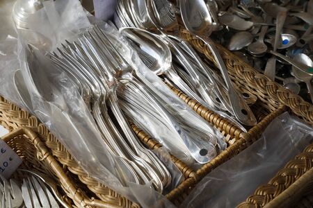 Nice, France - September 17, 2018: Many cutlery was placed in a wicker basket and put up for sale during the famous flea market called Cours Saleya.のeditorial素材