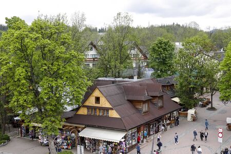 Zakopane, Poland - June 01, 2019: There is a wooden building with stores. You can see several other buildings, many trees and of course there are tourists walking around the area.のeditorial素材