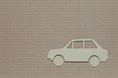 The flat car-shaped model is made of cardboard and is placed against a different type of cardboardの写真素材