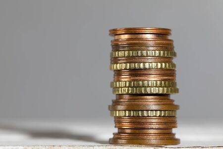 Various small euro coins of various colors have been stacked on top of each other.