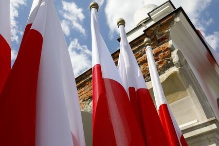 Flags of Poland against the background of brick detail of the building and blue sky with a few clouds.の写真素材