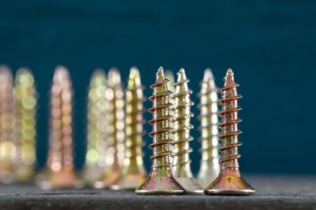 Group of self-tapping screws is shown up against colored background. These screws have flat heads.の写真素材
