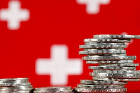 Group of various Swiss money coins shown against the background of the Swiss flag symbols.の写真素材