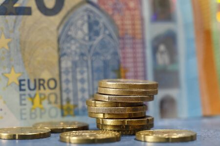 The banknote is in the background of the coins. The currency of the euro area have been in...