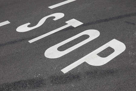 There is a stop inscription on the roadway. A stop sign has been placed on the asphalt road surface...