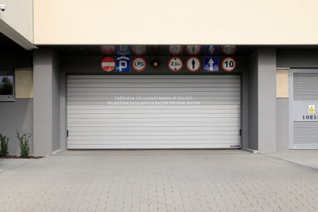 Warsaw, Poland - October 20, 2020: Entrance gate to the underground car park with a few road signs...