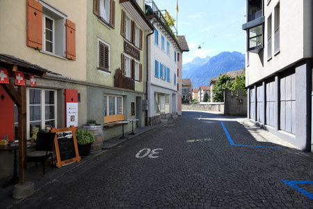 Fluelen, Switzerland - August 25, 2020: Cobbled street with a speed limit indicated on its surface and buildings on both sides. Now there is no traffic on the road.のeditorial素材