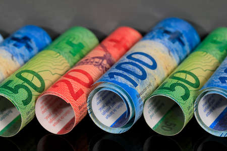 Swiss money. Swiss franc banknotes, several of which have been rolled up and placed side by side. CHF currency.の写真素材