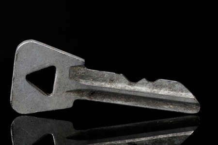 Old and no longer needed key seen against a black background.の写真素材