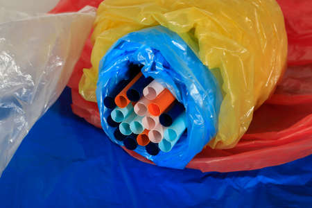 Drinking straw and crumpled plastic material. Plastic disposable items are comfortable and easy to...