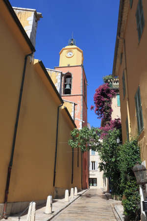 Saint-Tropez, France - July 08, 2009: On the narrow street there is a bell tower, which also houses a clock. There is no traffic on the street now.のeditorial素材