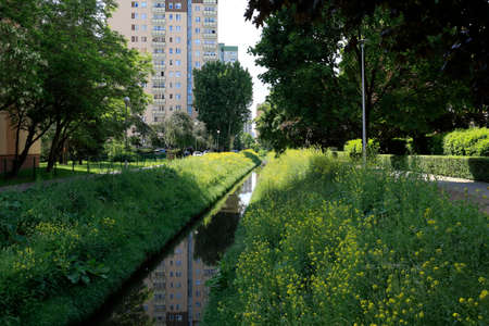 There is a narrow canal in the housing estate. This part of Warsaw is called Goclaw, there are many houses and lots of vegetation.の写真素材