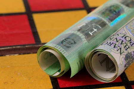 The rolls of Polish paper money and the Euro express the relationship between Euro money and Polish zloty. PLN and EUR currencies placed on chessboard.の写真素材