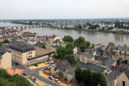 Saumur, France - June 13, 2010: There are residential buildings of this magnificent city visible along the river. The banks of the Loire River are connected by a stone bridge.のeditorial素材