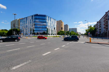 Warsaw, Poland - June 14, 2021: Modern building is on the other side of intersection of wide streets...