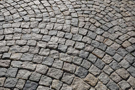 Many small stone blocks stacked side by side make up the surface of a paved road or sidewalk.