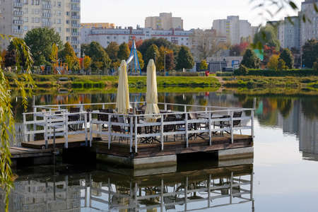 Warsaw, Poland - October 11, 2021: The cafe deck on the lake waters it is an outdoor part of a cafe operating on the shore of the lake. This is a part of park area of Goclaw housing district.のeditorial素材