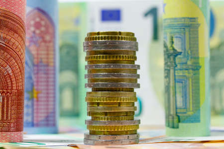 A pile of European Union coins shown together with banknotes. Euro banknotes are not made of paper, but of pure cotton fiber to improve their durability. EUR currency.の写真素材