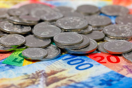 A group of Swiss franc coins and banknotes of different denominations, placed next to each other....