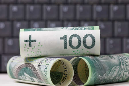 Polish zloty banknotes stacked against a dark background of a computer keyboard, PLN currencyの写真素材