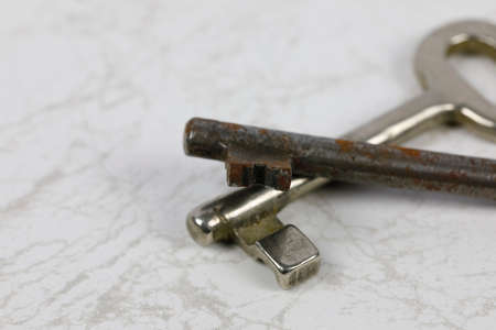 Two old keys for the door lock were set against a marble backgroundの写真素材