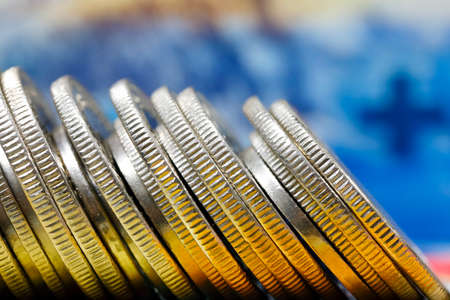 CHF currency. Swiss franc coins stacked side by side against a background of banknotes are now a...