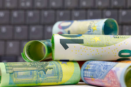 There are European Union banknotes placed against  a computer keyboard background. Euro banknotes are not made of paper, but of pure cotton fiber to improve their durability. EUR currency.の写真素材