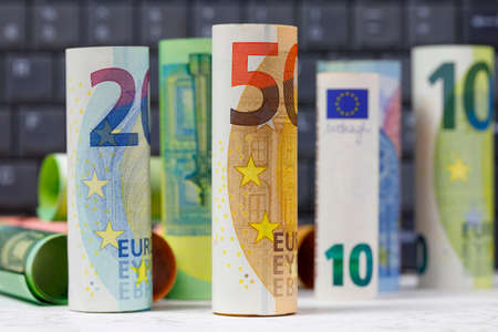 There are European Union banknotes placed against  a computer keyboard background. Euro banknotes are not made of paper, but of pure cotton fiber to improve their durability. EUR currency.の写真素材