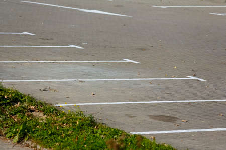 The area covered with concrete paving stones with painted white lines marking the parking spaces is part of a larger outdoor area of the car park which is now vacant.の写真素材