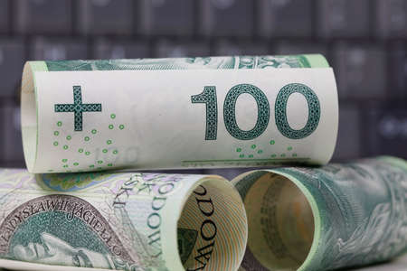 A group of Polish zloty banknotes stacked against a dark background of a computer keyboard, PLN currencyの写真素材