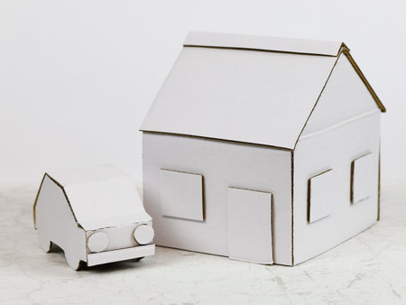 The house model together with the car model nearby are made of white cardboard. Together, these two items symbolize property, family home or mortgage, or other real estate meanings.の写真素材