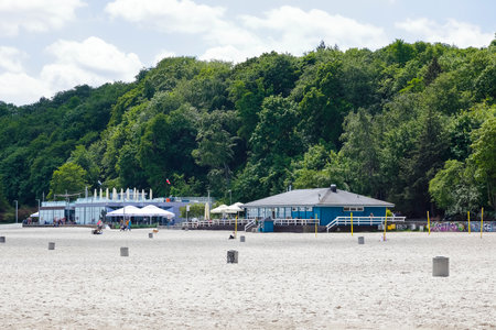 Gdynia, Poland - June 3, 2022: There are dense deciduous trees in the background and next to them, next to the beach, there are one-story restaurant buildings.のeditorial素材