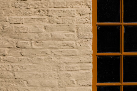 Near the narrow-frame window, you can see a brick wall with a yellow coating applied
