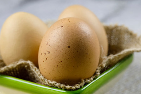 Three boiled hen's eggs are on a piece of linen cloth and have been so placed in a small ceramic bowlの写真素材