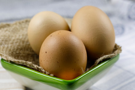 Three boiled hen's eggs are on a piece of linen cloth and have been so placed in a small ceramic bowlの写真素材