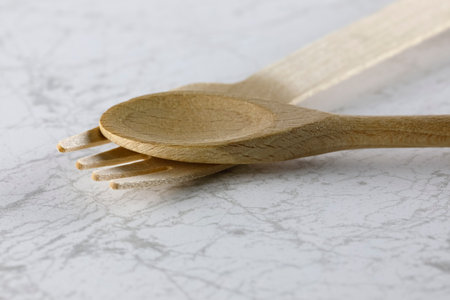One spoon and one fork made of natural material such as wood have been placed on a marble countertopの写真素材