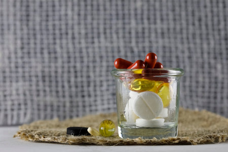 There is a large dose of various medicines in the glass container and next to it, and you can see it against the background of the fibers of the fabricの写真素材
