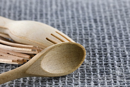 One spoon and a few forks made of natural material such as wood have been placed on a synthetic fiber fabricの写真素材